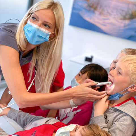 Frau zeigt den Kindern die intraorale Kamera.
